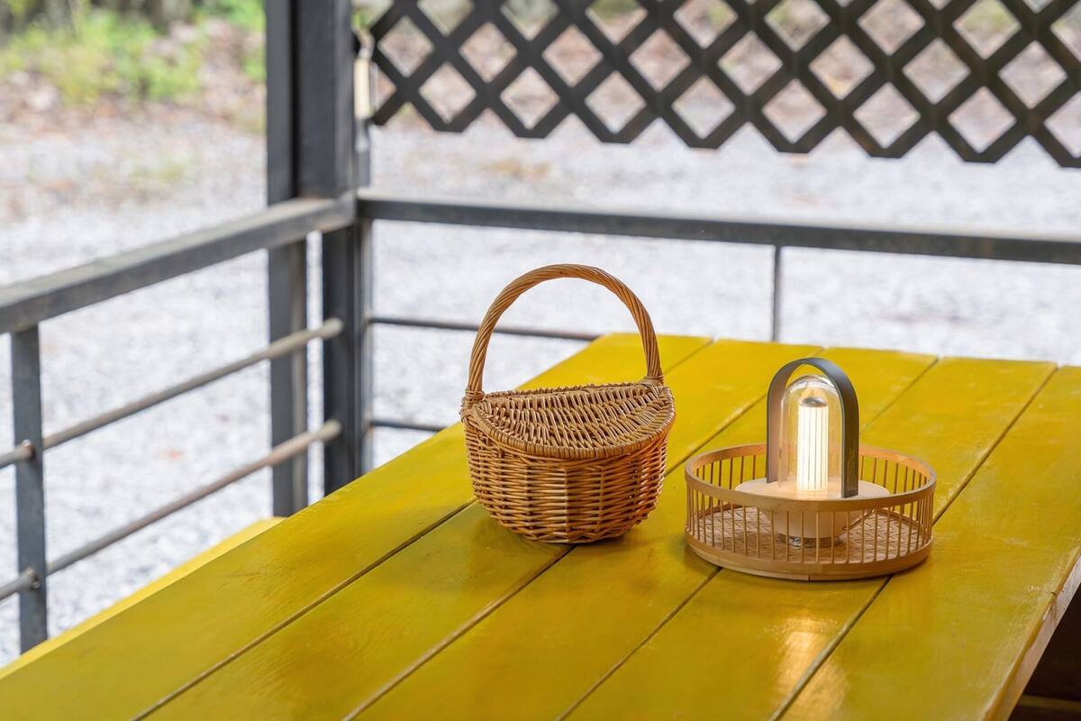 Un panier en osier et une lanterne sur une table jaune.