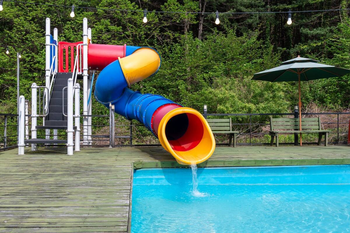 Un toboggan aquatique avec un tube bleu et jaune qui débouche dans une piscine.