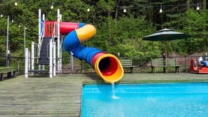 A water slide with a blue and yellow tube leading into a pool.
