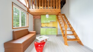 Un interior moderno con una escalera de madera, una cocina verde, un sofá de cuero y una silla roja.