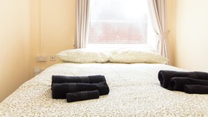 A hotel room with a bed, two pillows, and two rolled towels on the bed. - Brookvale Guest House Room 4 (Southampton)