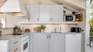 Una cocina moderna con armarios blancos, microondas integrado y estufa.