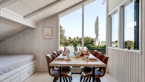 Un comedor con una mesa larga, varias sillas y vistas al exterior con vegetación.