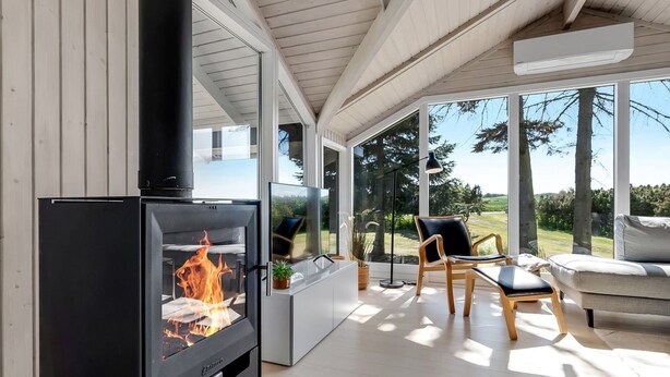 Una sala de estar moderna con estufa de leña, ventanas amplias y vistas al exterior.