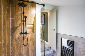 A modern bathroom with a glass shower enclosure, wooden flooring, and a towel rack. - The City Centre Studios (Peterborough)