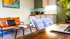 A modern living room with a sofa, a coffee table, and a laptop on a wooden table. - The City Centre Studios (Peterborough)