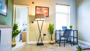 A room with a desk, chair, floor lamp, and potted plants. - The City Centre Studios (Peterborough)