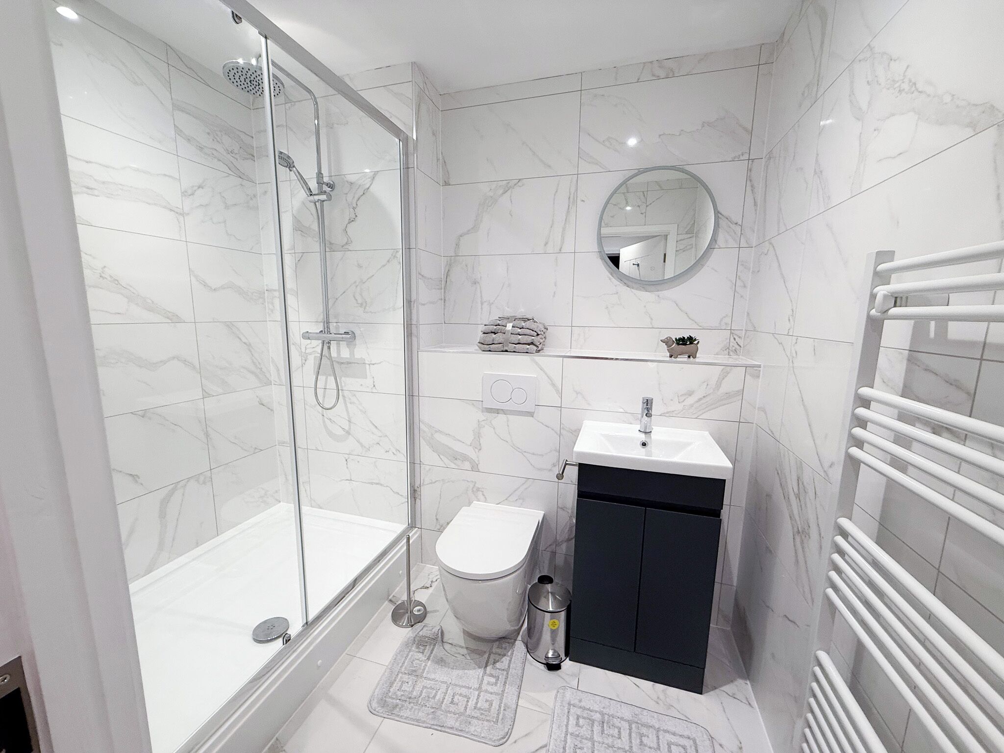 A modern bathroom with a glass-enclosed shower, a toilet, a sink, and a mirror.