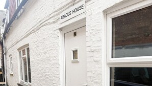 A white building with a sign reading 'ABACUS HOUSE.' There is a door with a small window above it, and a window with blinds to the right. - Abacus House Apartments (Huntingdon)