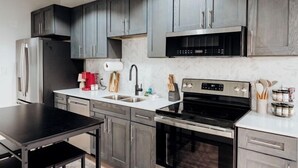 Una cucina moderna con mobili scuri in legno, elettrodomestici in acciaio inossidabile e una parete a schienale in marmo.
