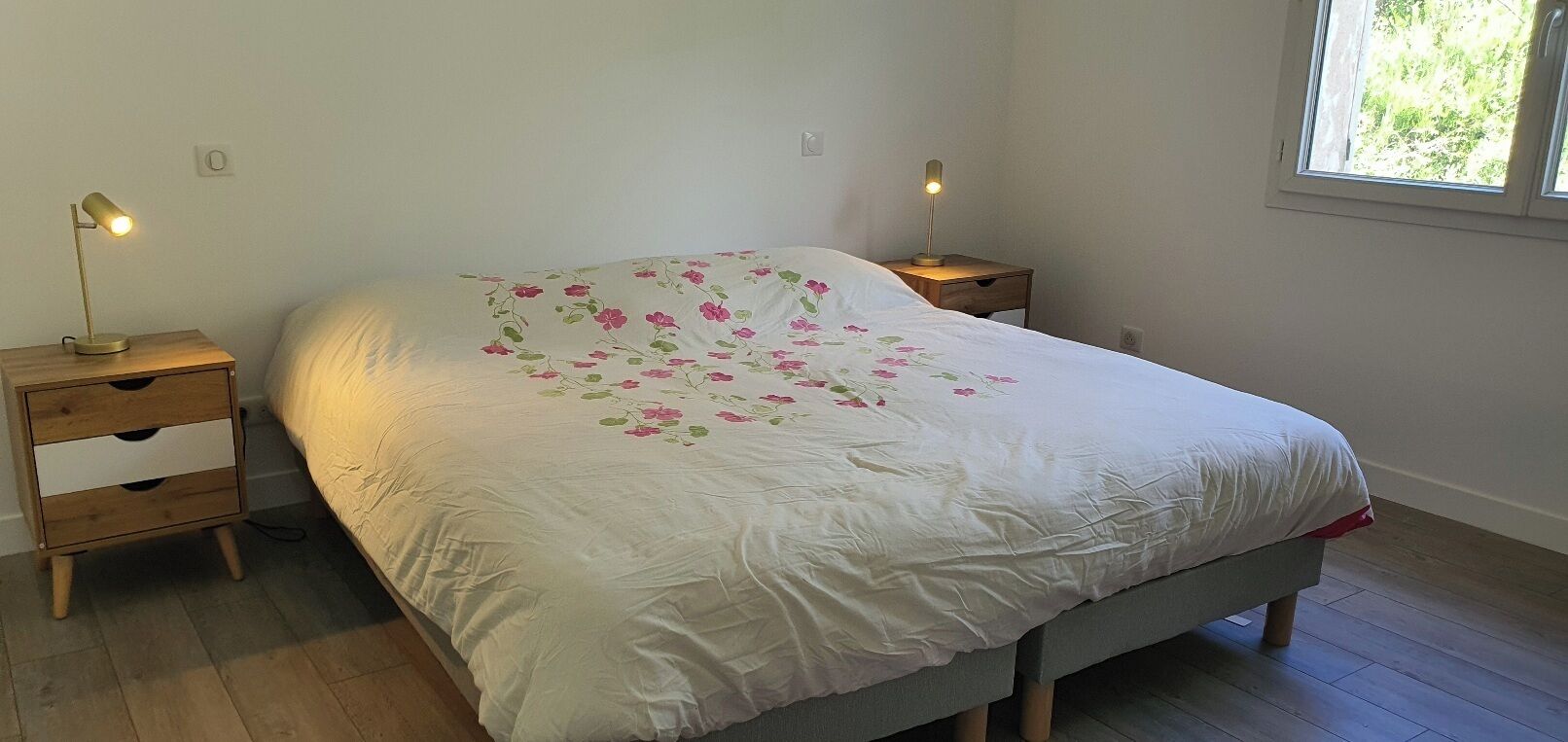Ein Schlafzimmer mit einem Bett, zwei Nachttischen und einem Fenster.