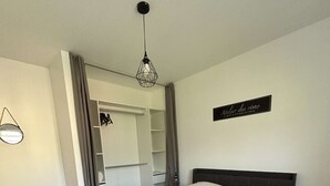 Ein ordentlich eingerichtetes Schlafzimmer mit einem großen Bett, einem Kleiderschrank, einem Nachttisch und einer Pendelleuchte.