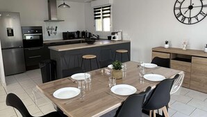 Eine moderne Küche mit Essbereich, mit einem Holztisch, schwarzen Stühlen und einer Uhr an der Wand.