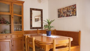 Un comedor con mesa de madera, sillas, un armario y una planta en maceta.