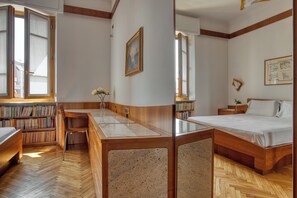 A room with a wooden desk, bookshelves, a bed, and a window. - JOIVY Captivating flat with balcony (Milan)