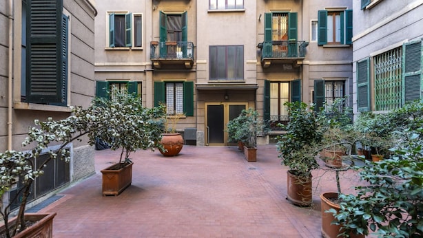A courtyard with potted plants, a central door, and a brick floor.