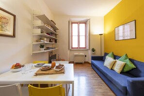 Un coin repas avec une table blanche, des chaises jaunes et un canapé bleu.
