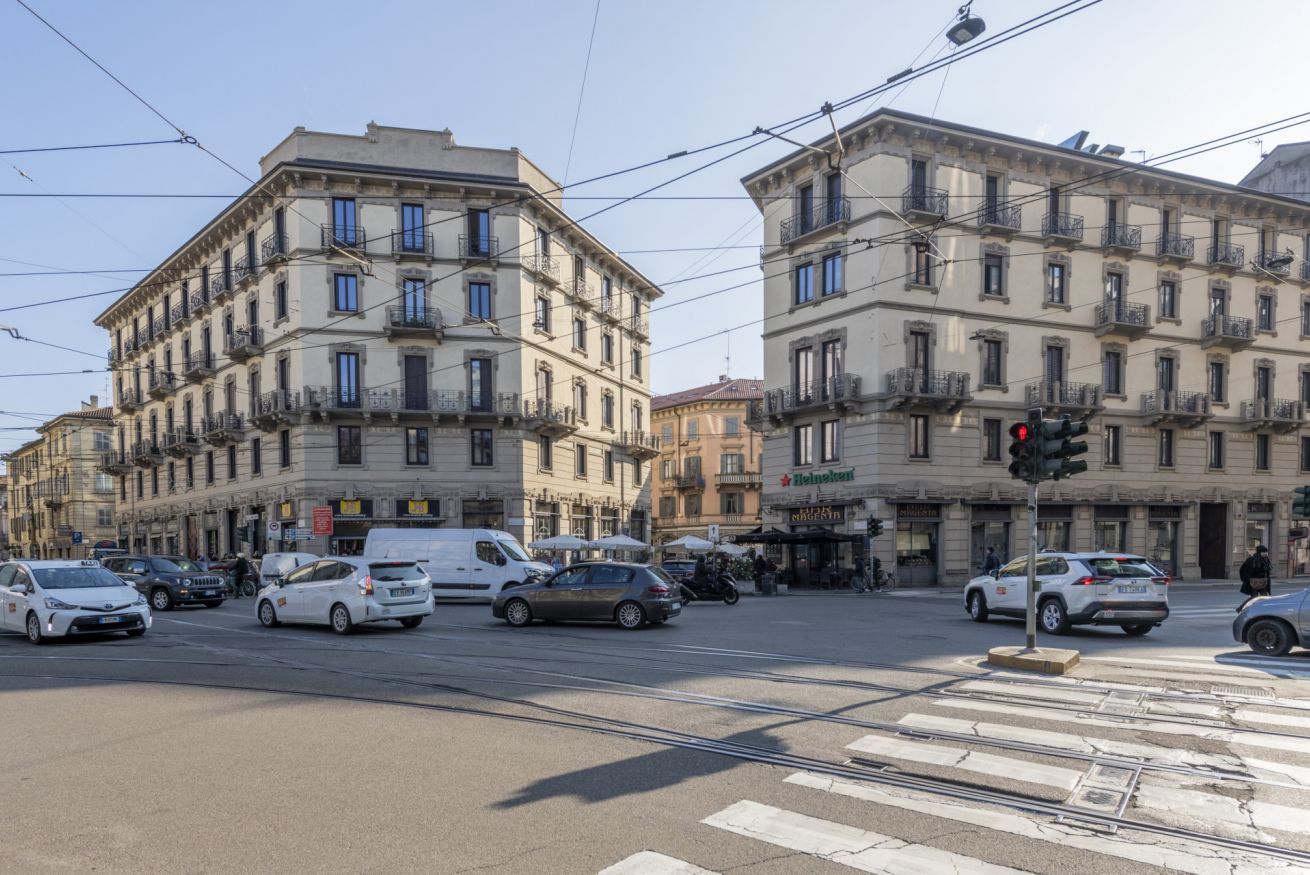 Une intersection où se croisent des rues bordées de bâtiments historiques, une ligne de tramway et un passage piéton.