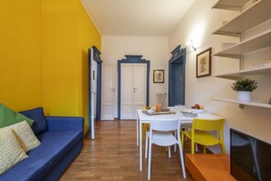 A compact living space with a sofa, dining table, chairs, and a TV.