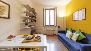 A dining area with a white table, yellow chairs, and a blue sofa.