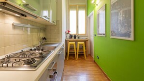 A kitchen with a gas stove, wooden stools, and framed pictures on the wall.