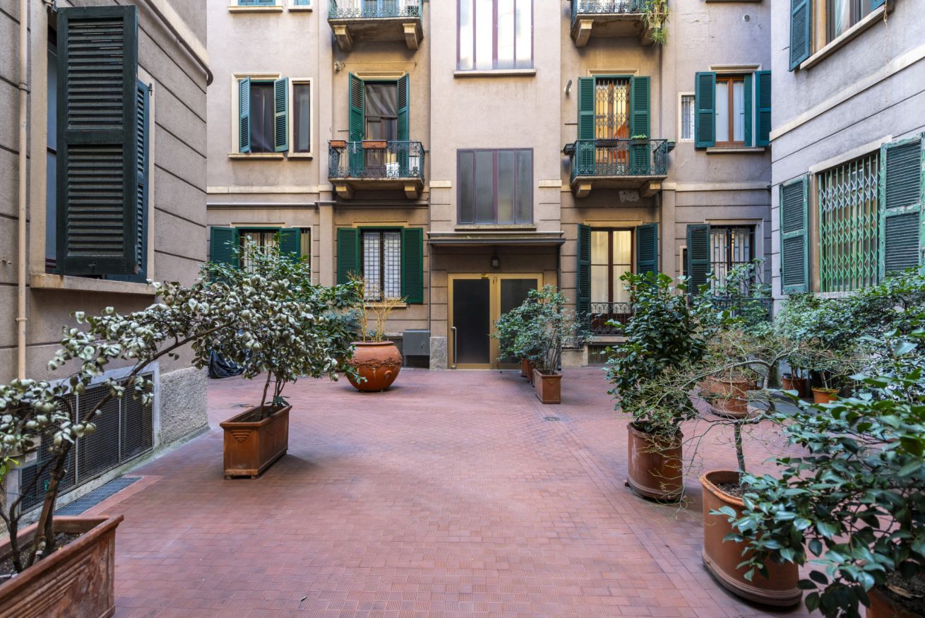 A courtyard with potted plants, a central door, and a brick floor.