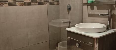 Ein modernes Badezimmer mit einer begehbaren Glasdusche, einem Waschbecken mit Spiegel und einer gefliesten Wand mit Schachbrettmuster.