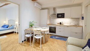 A compact kitchen with white cabinets, a microwave, and an oven. There is a dining table with chairs and a small potted plant. - Gorgeous apartment in Camogli with WiFi (Camogli)