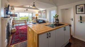 Una cocina amplia con una isla de madera, armarios blancos y un ventanal con vistas a un balcón.