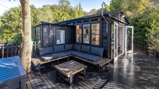 Una terraza de madera con una zona de estar integrada y una pequeña mesa.