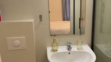 Un baño con lavamanos blanco, un espejo, toallero y un inodoro.