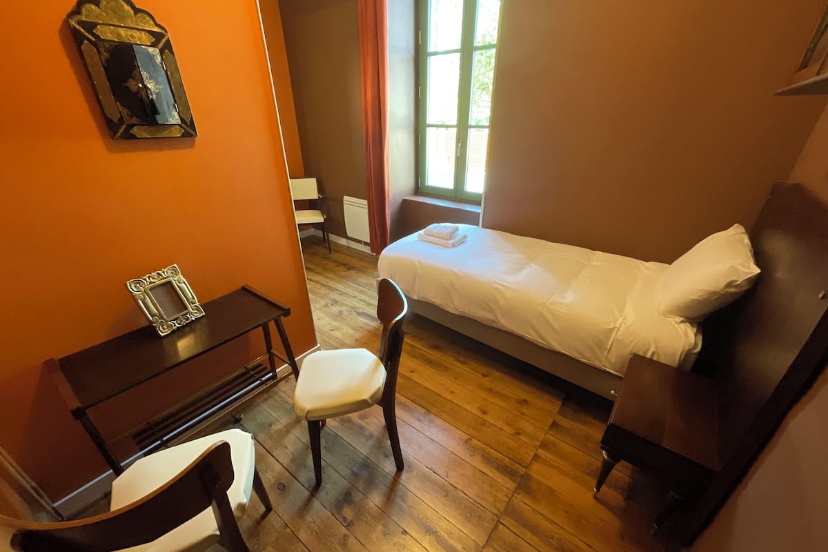 Una habitación pequeña y acogedora con una cama individual, un escritorio y una silla.