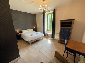 A bedroom with a bed, bedside tables, a chandelier, a window with curtains, a radiator, and a wooden cabinet. - TAVARN TY GAR (Hennebont)