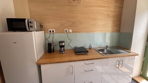 A compact kitchen with a microwave, coffee maker, and a digital scale on the counter. - TAVARN TY GAR (Hennebont)