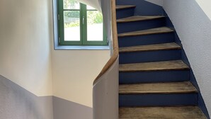 A spiral staircase with wooden steps and a white handrail, leading to a landing with a small window. - TAVARN TY GAR (Hennebont)