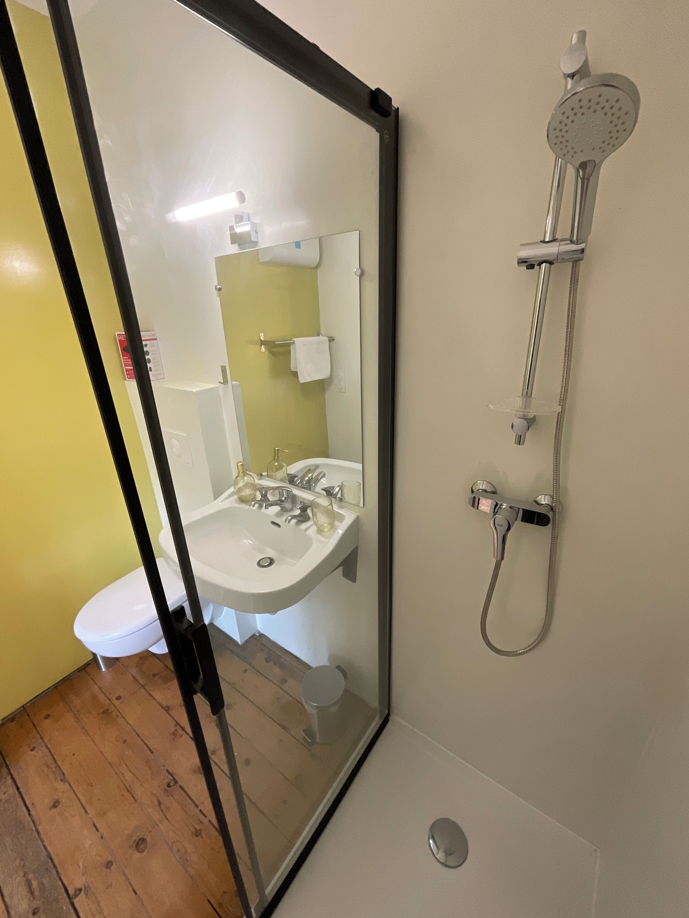 A bathroom with a glass partition, a sink, a toilet, and a shower.