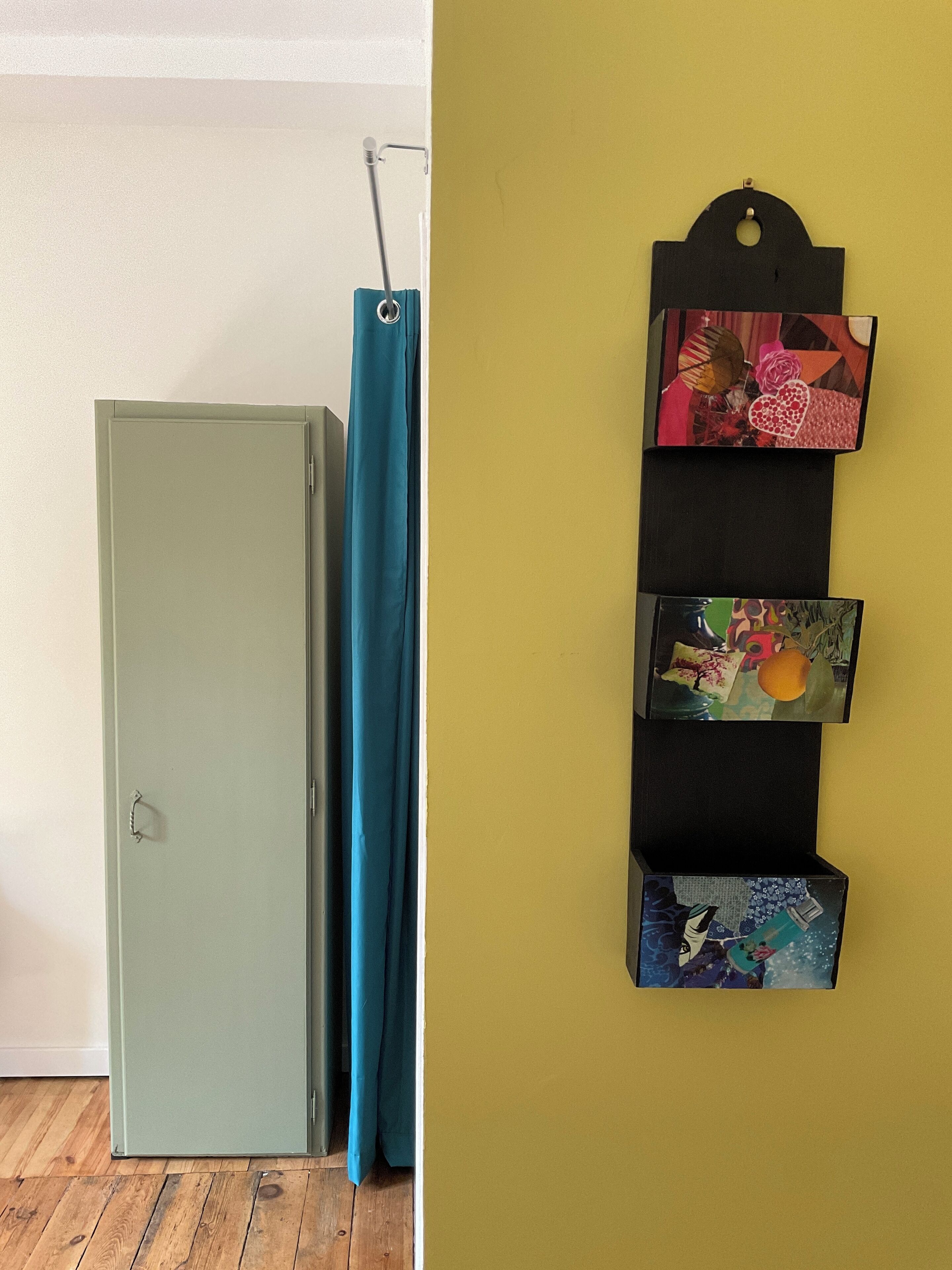 Une pièce avec des rideaux turquoise, une porte turquoise et un mur où sont accrochées des photos.