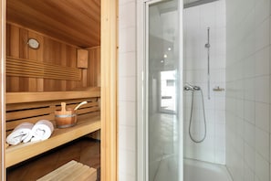 A wooden sauna with a glass door, a wooden bench, a wooden bucket, and a towel. - Casa Andy 2 Val Lavizzara (Lavizzara)