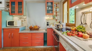 Cucina con mobili rossi, un forno a microonde e diversi prodotti freschi sul piano di lavoro.