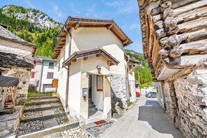 Une rue étroite bordée de bâtiments traditionnels en pierre, avec un escalier en bois et un ciel dégagé.