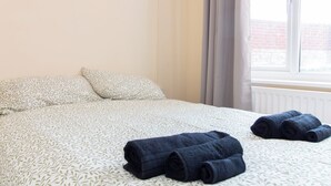 Une chambre d’hôtel avec un lit, deux oreillers et des serviettes enroulées posées sur le lit.