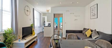 A modern living room with a TV, sofa, and dining area.
