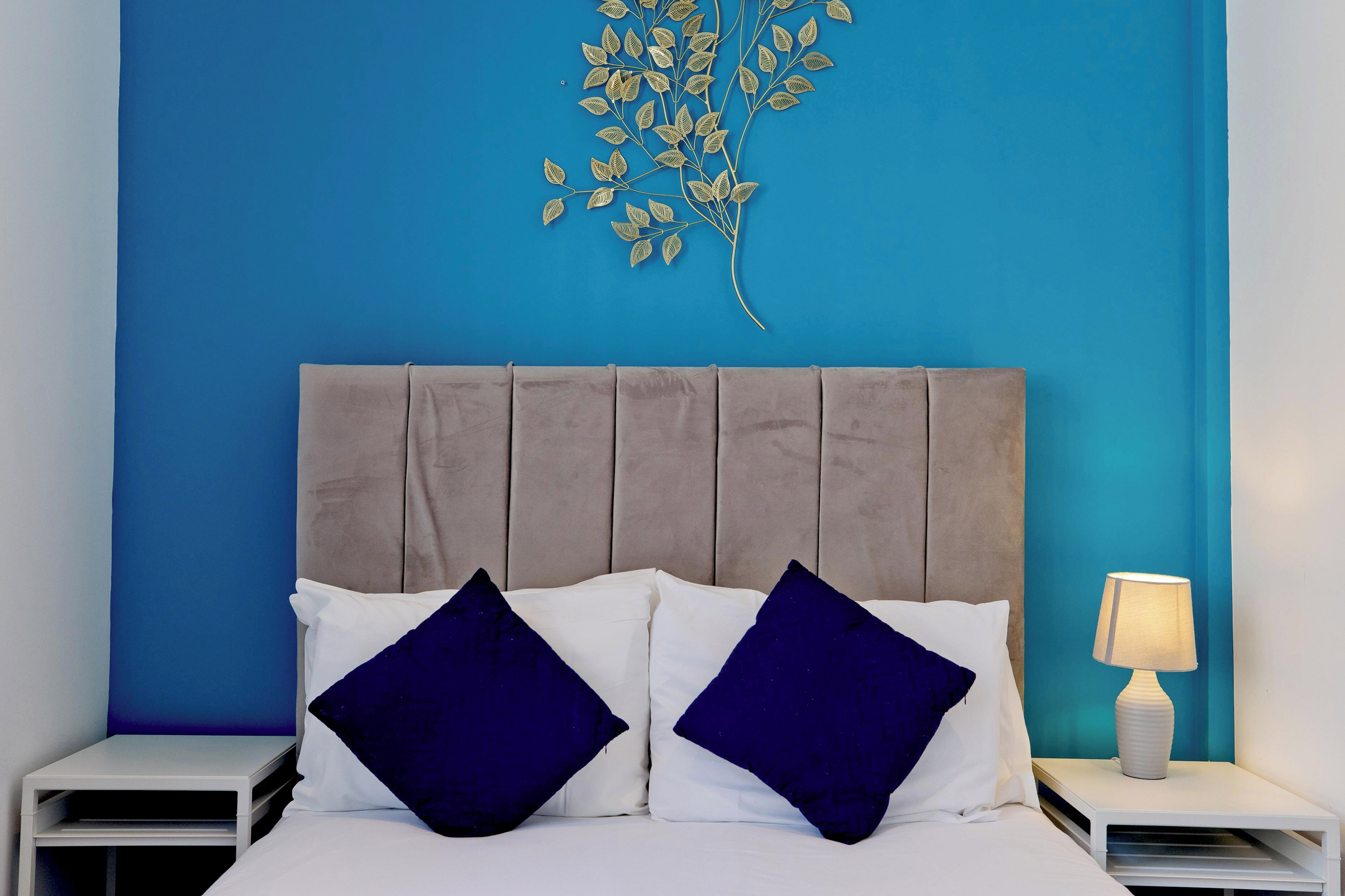 Ein Bett mit Kopfteil, zwei Kissen, ein Nachttisch und eine Wandleuchte.