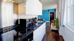 A modern kitchen with white cabinets, a black countertop, and a stainless steel stove. - Imperial Middlesex Street Apartments (London)
