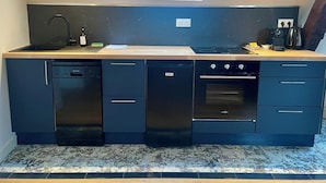 Cocina compacta con lavavajillas, horno y una pequeña zona de encimera.