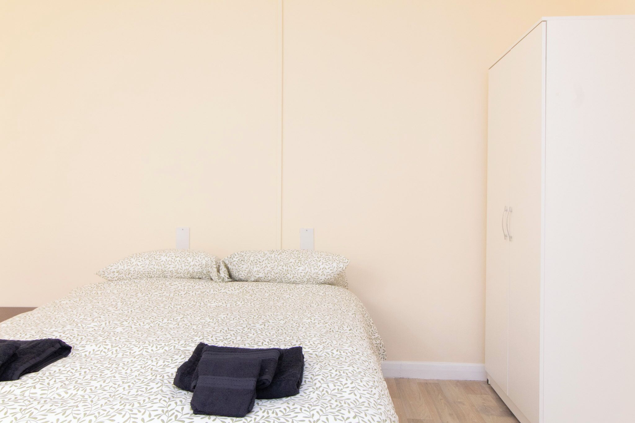 Une chambre à coucher avec un lit, deux oreillers, une armoire et une paire de serviettes sur le lit.