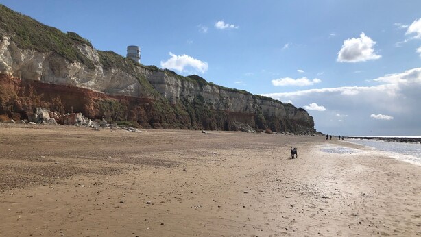A beach with a rocky cliff and a lighthouse. - Fabulous Seaside Retreat (Hunstanton)