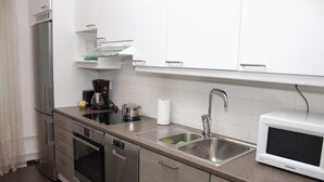 A modern kitchen with stainless steel appliances, a microwave, and a sink. - Kotimaailma CenterHouse studio (Lahti)