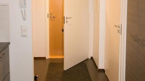 A hallway with a carpet, a phone on the wall, and a door leading to another room. - Kotimaailma CenterHouse studio (Lahti)