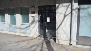 A building entrance with a glass door, a keypad lock, and a small sign above the door. - Kotimaailma CenterHouse studio (Lahti)